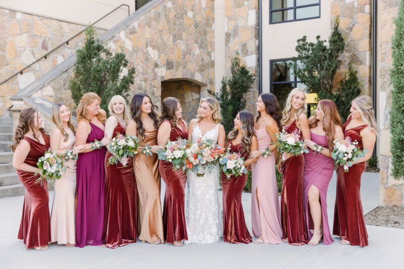 Bride and bridesmaids in varied pink dresses with bouquets.